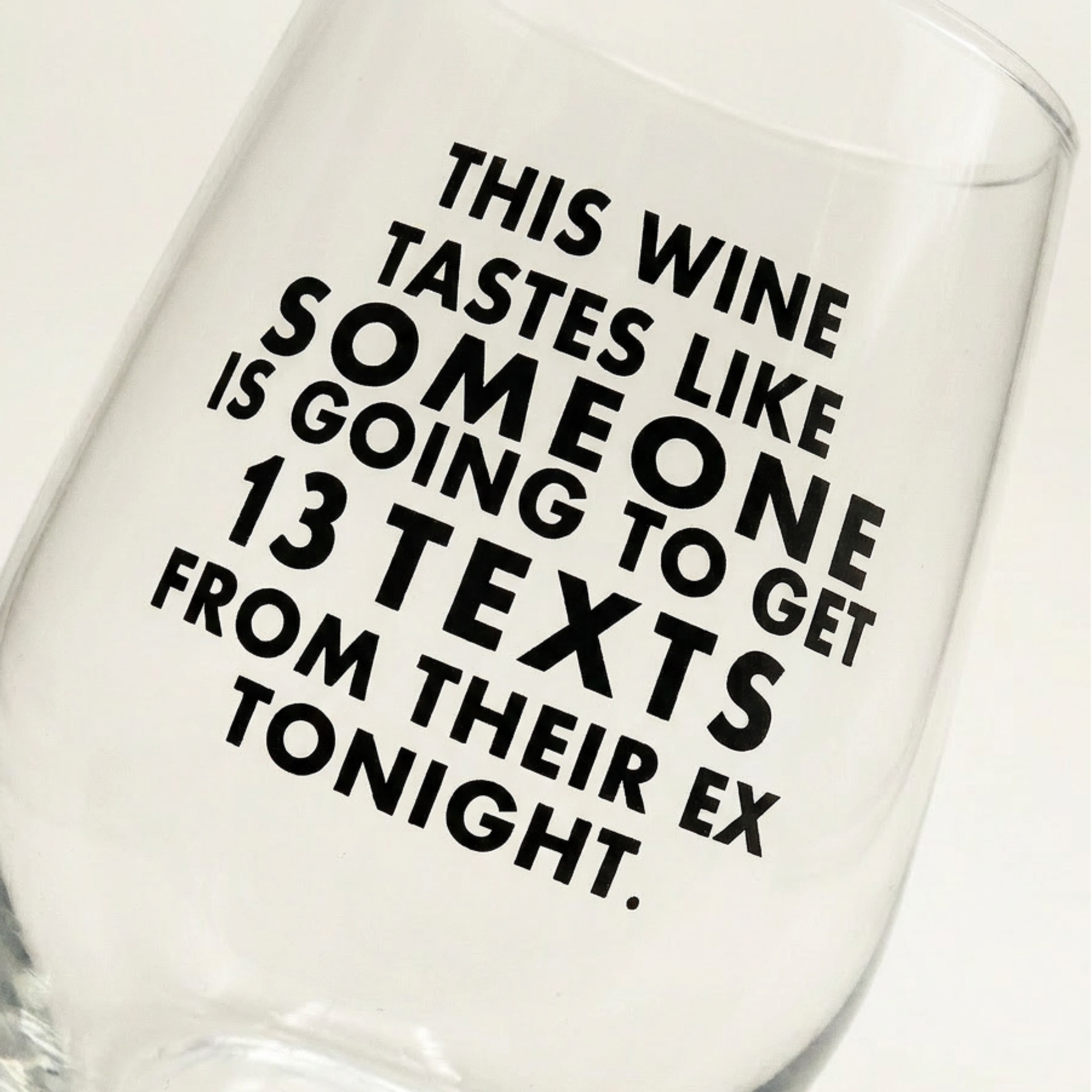 Clear wine glass with humorous text design on a white background