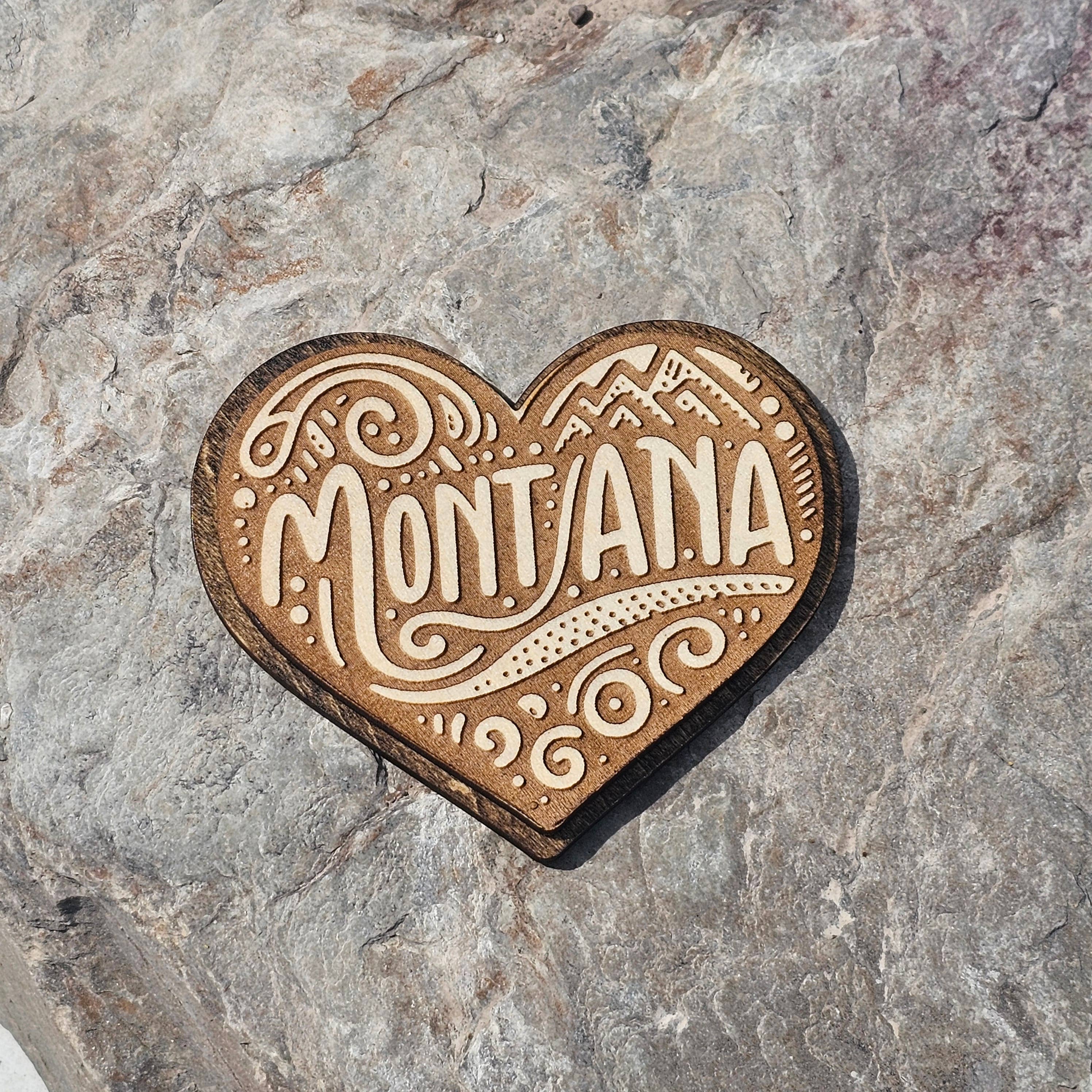 Heart shaped wood magnet engraved with Montana hand lettering, mountains, and folk art swirls, from The Ruddy Duck in Whitefish, Montana
