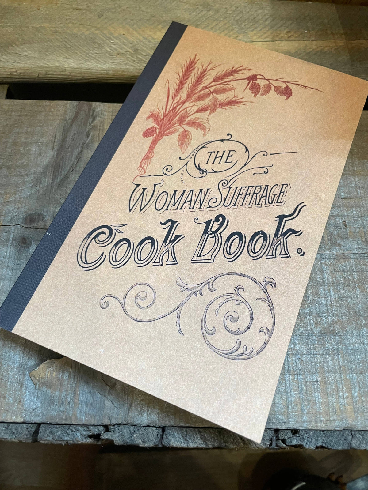 Paperback copy of The Woman Suffrage Cook Book on a rustic wooden table