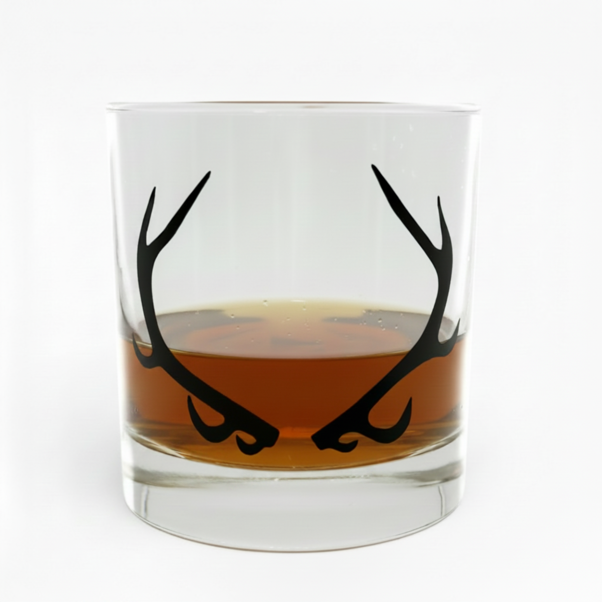 Glass with black antler design filled with amber liquid on a white background