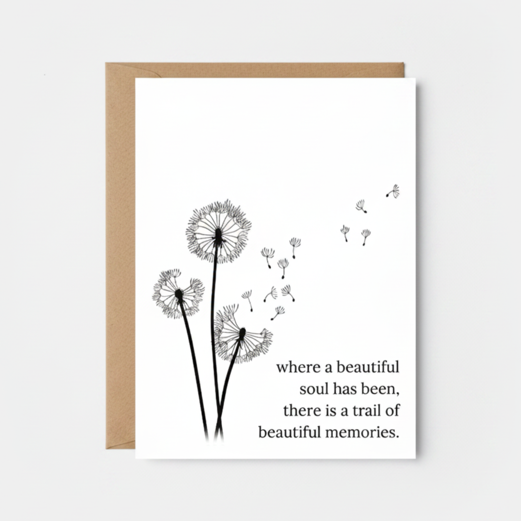 Greeting card with dandelion illustration and quote on a white surface with candles.