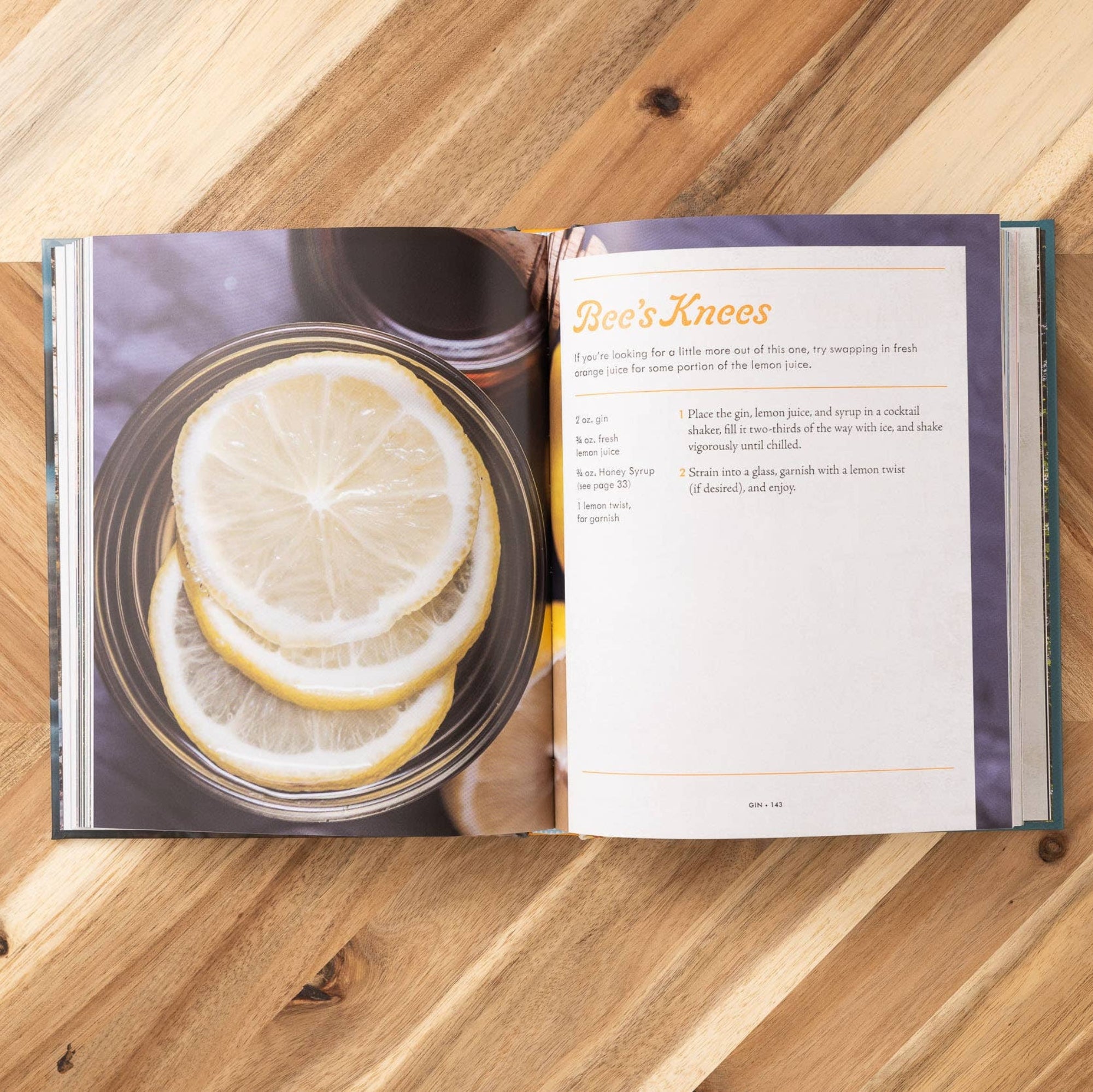 Open cookbook on a wooden surface with lemon slices and tea.