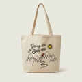 Beige tote bag with mountain and sun design on a white background
