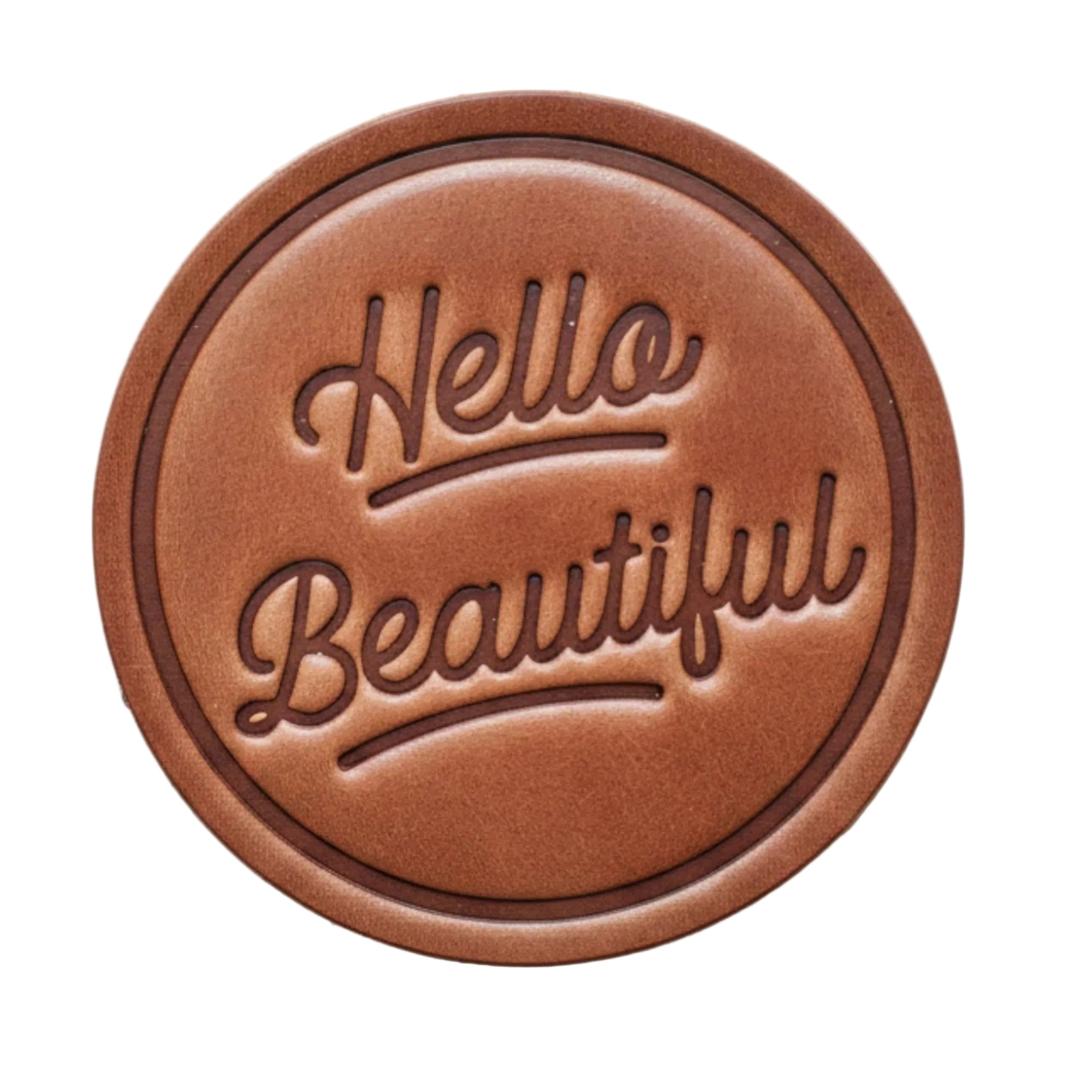 Round brown leather patch with 'Hello Beautiful' text on a wooden background
