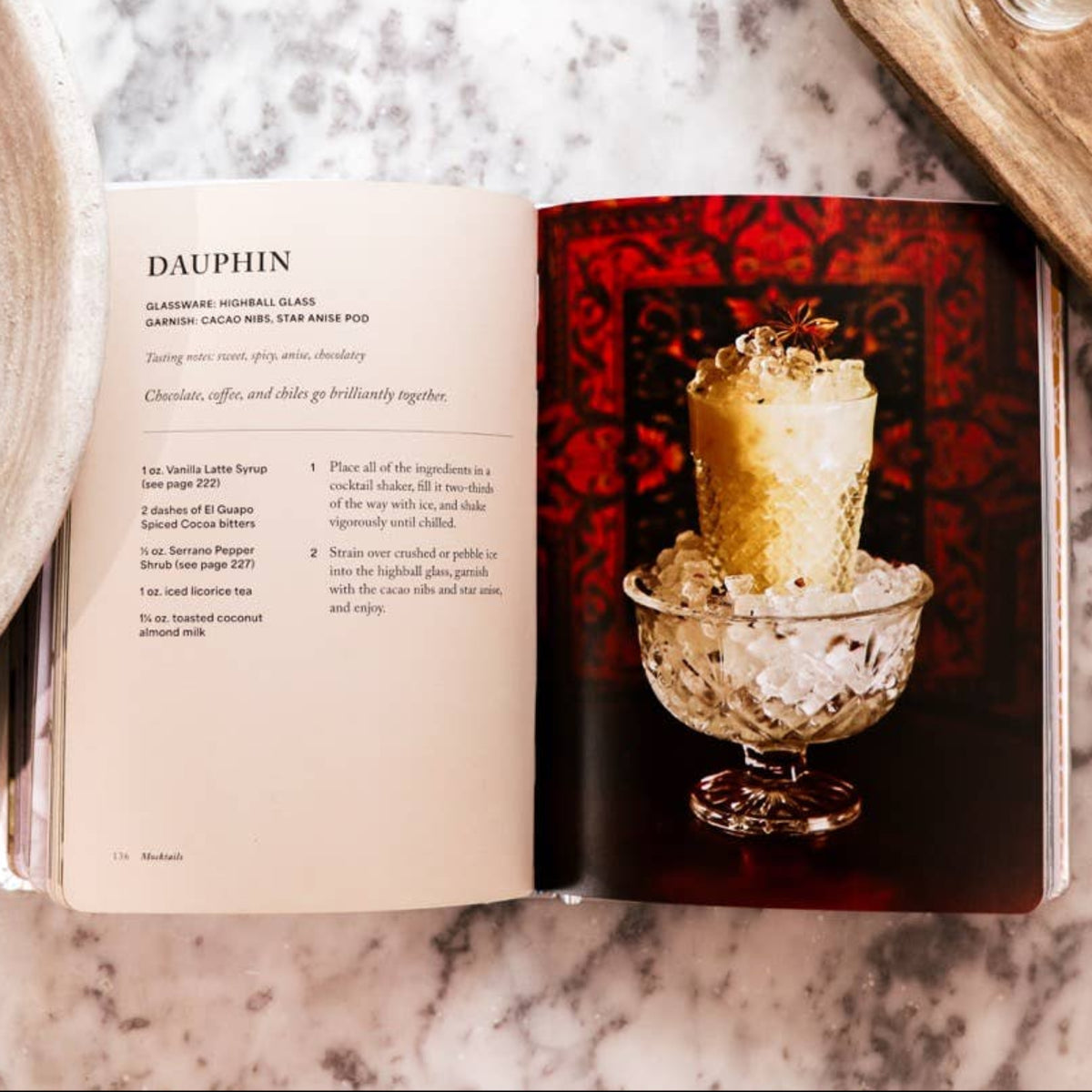 Open book with a candle illustration on a marble surface with decorative elements.