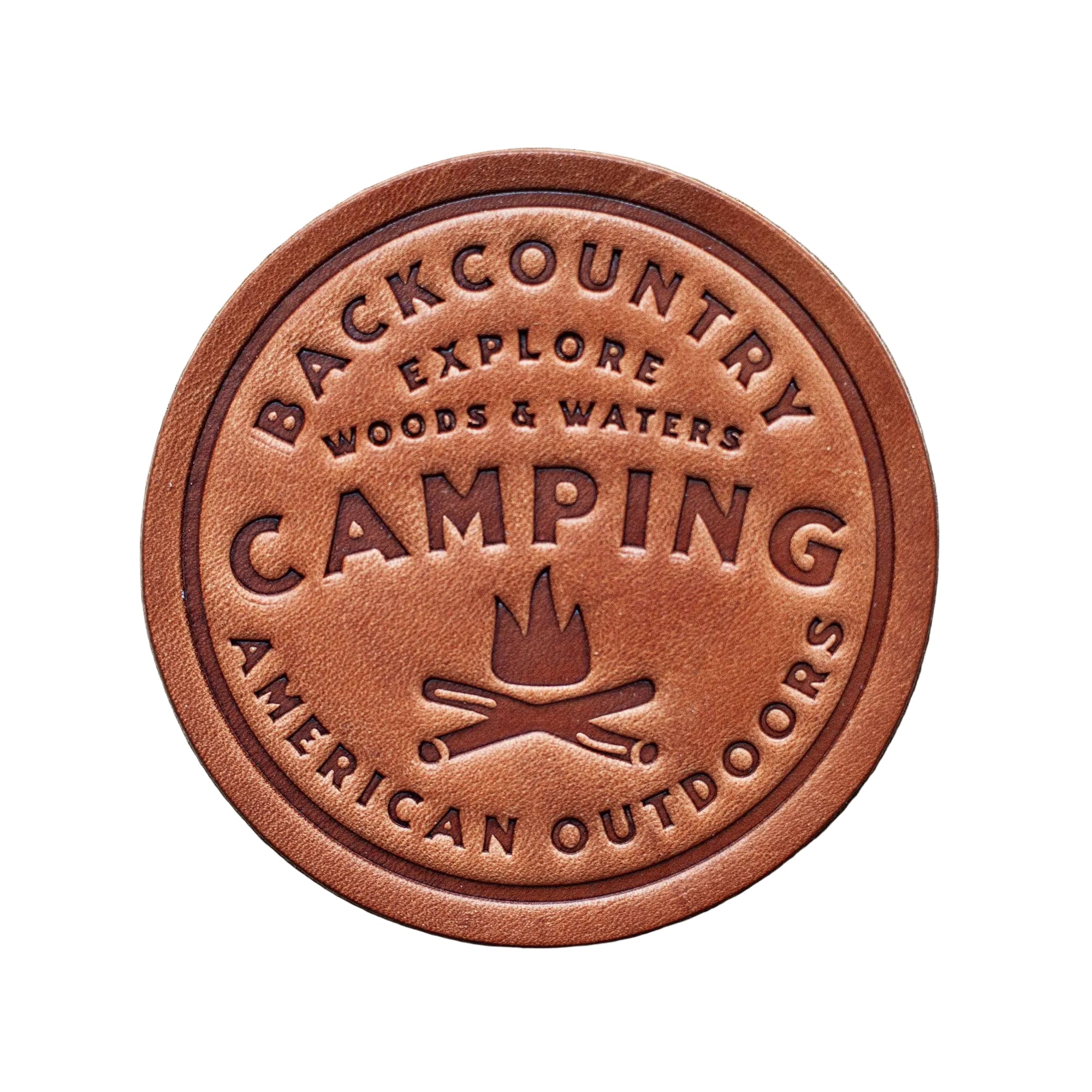 Round leather patch with 'Backcountry Camping' text and campfire graphic on a wooden background