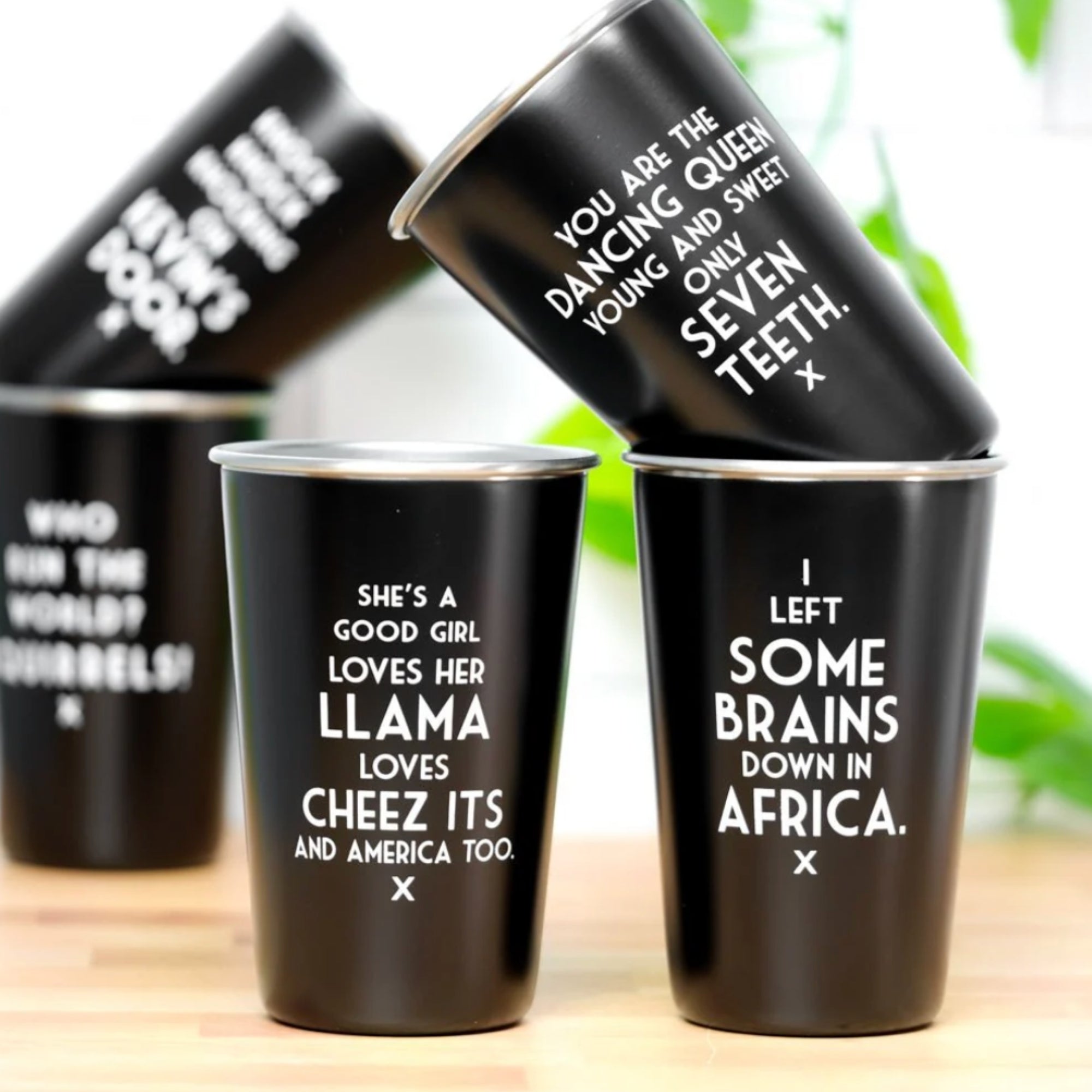Black cups with white text on a wooden surface