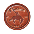 Brown leather medallion with 'Montana' and horse design on a wooden background