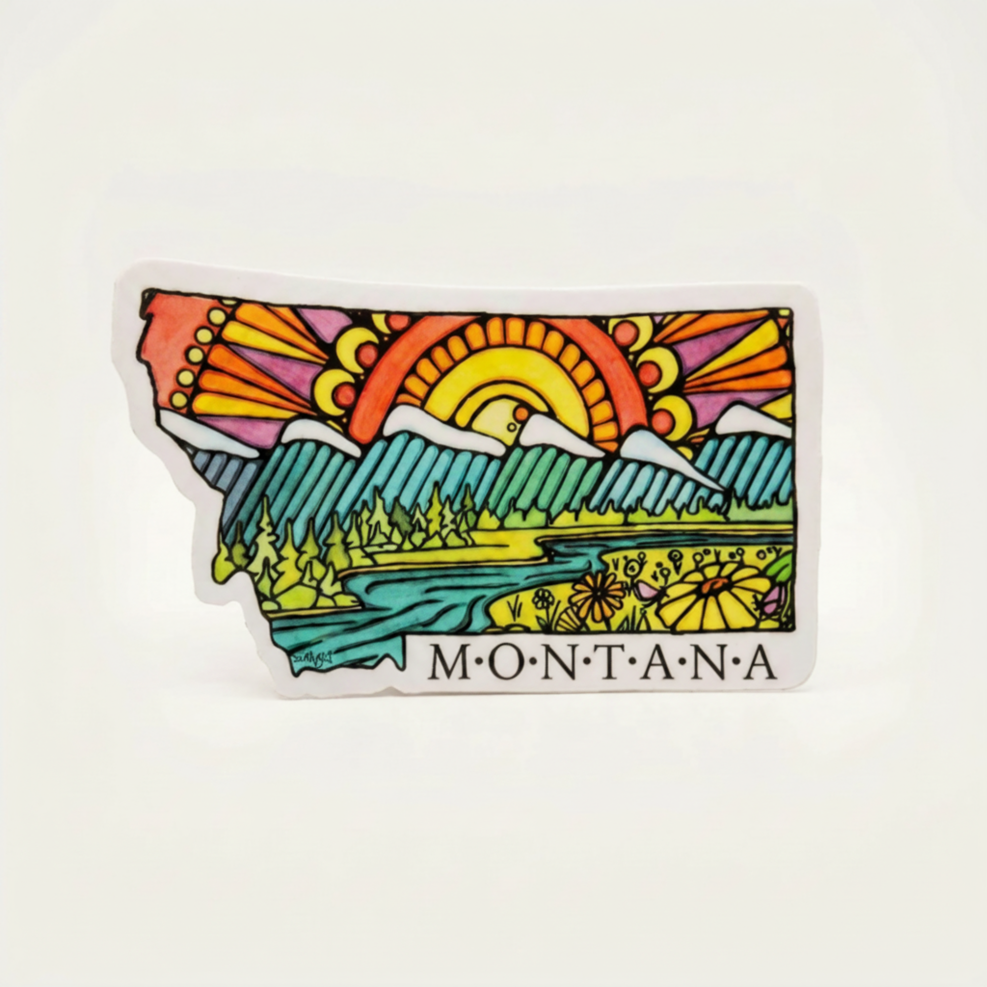 Colorful sticker shaped like the state of Montana with a landscape design on a white background.