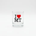 Clear glass shot glass with 'I ❤️ MT' text on a wooden surface