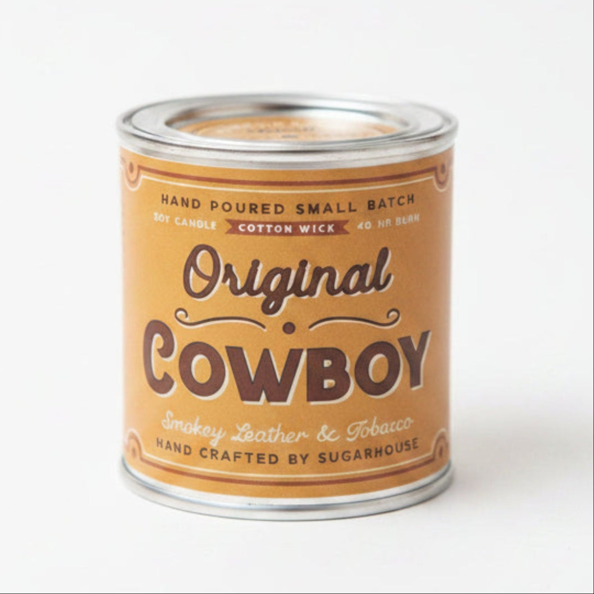 Can of 'Original Cowboy' candle on a wooden surface with a blurred background