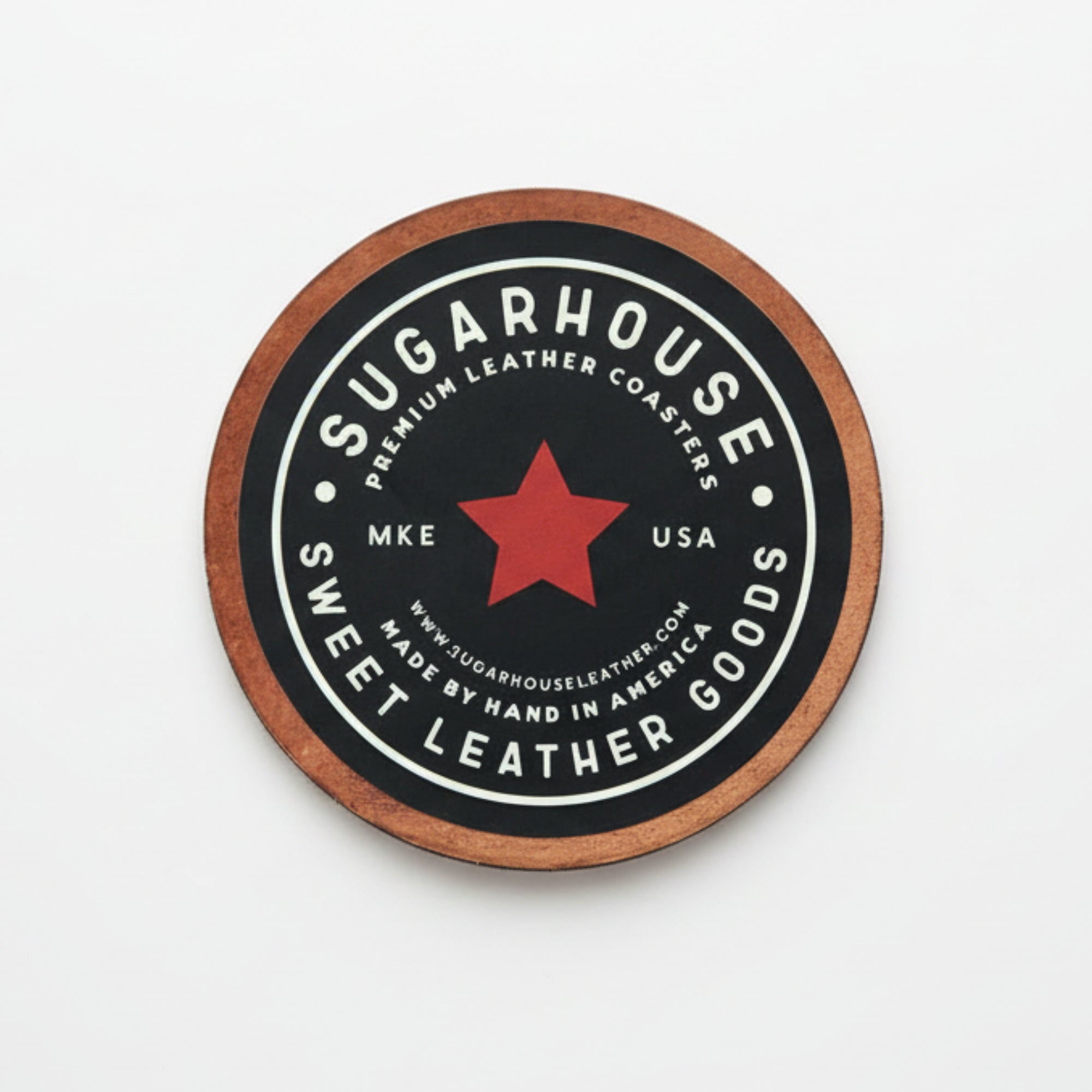 Round leather coaster with 'Sugarhouse Leather Goods' branding on a wooden surface