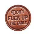 Brown leather plaque with engraved text on a wooden background