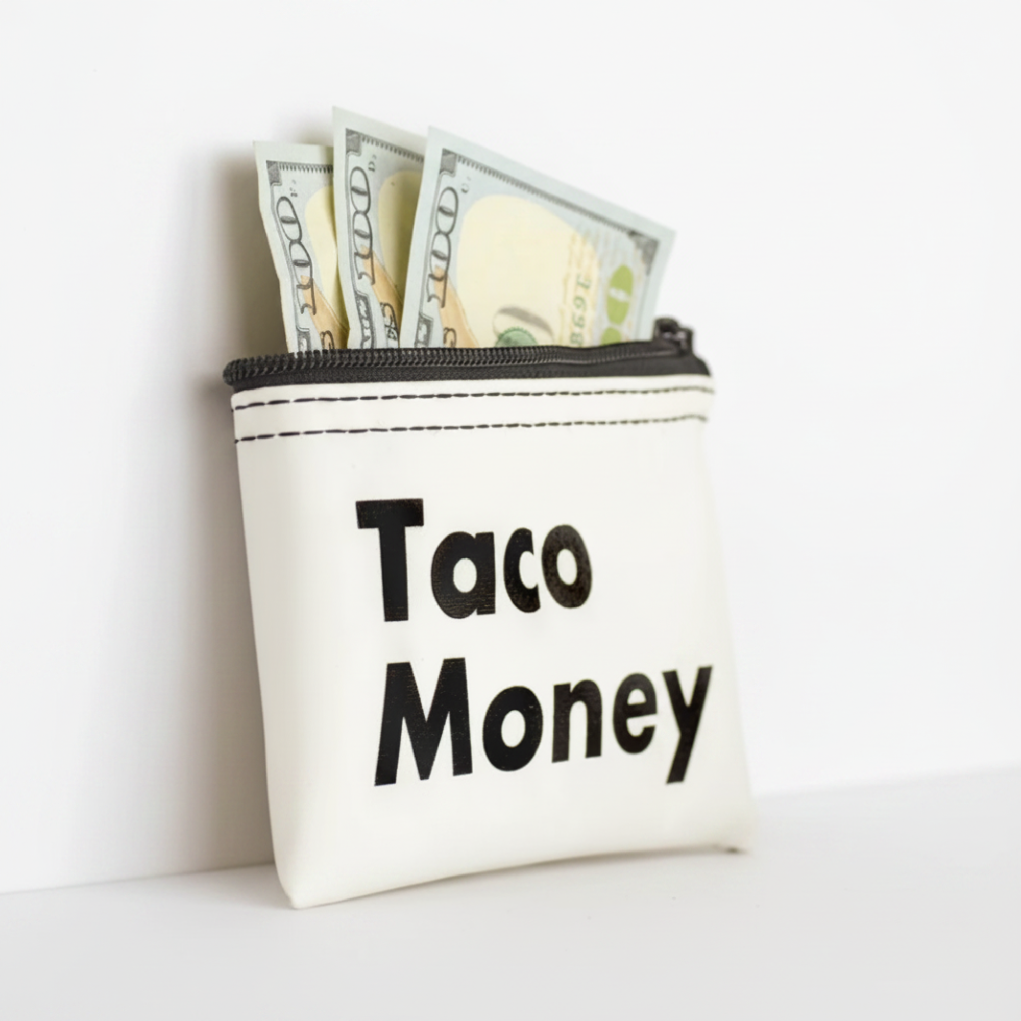 Small pouch labeled 'Taco Money' with dollar bills inside, on a light background