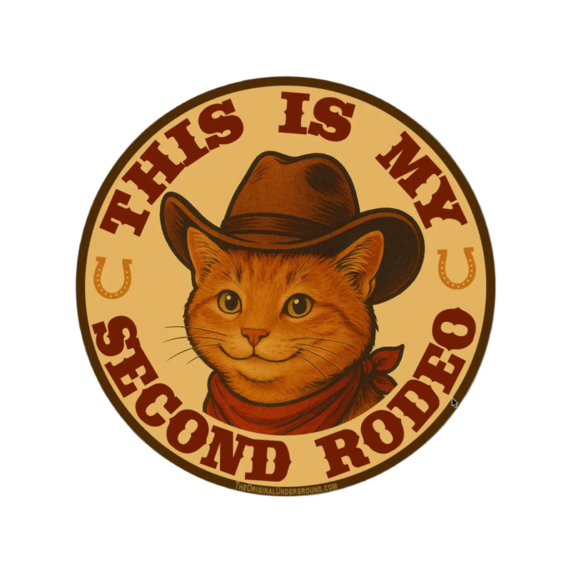 Circular sign with a cat wearing a cowboy hat and text 'This is my second rodeo' on a beige background.