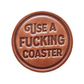 Round brown leather patch with embossed text on a wooden background