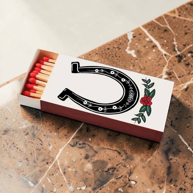 Decorative matchbox with lucky horseshoe western design holding 40 long wooden matches, from The Ruddy Duck in Whitefish, Montana