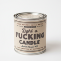 Candle in a can with a humorous label on a wooden surface